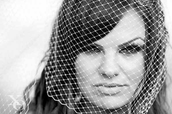 Black and white portrait of a bride behind a birdcage veil