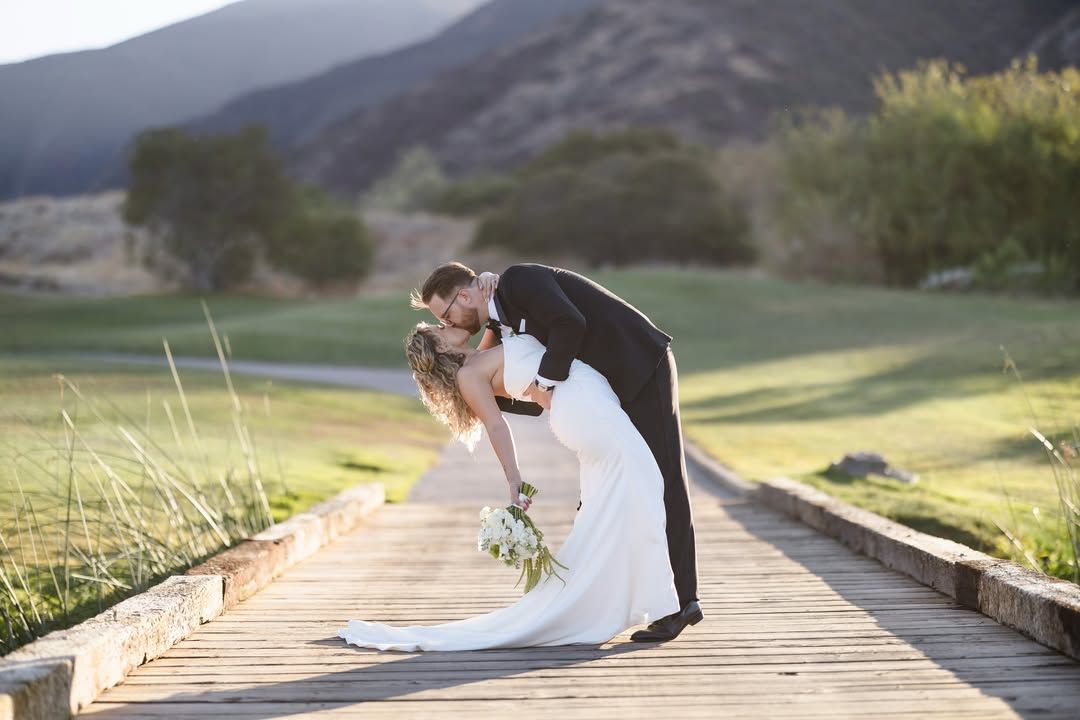 Groom dipping the bride for a kiss on a boardwalk at golden hour